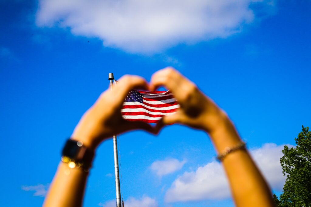 Intercâmbio nos Estados Unidos - Mãos em formato de coração na bandeira dos EUA