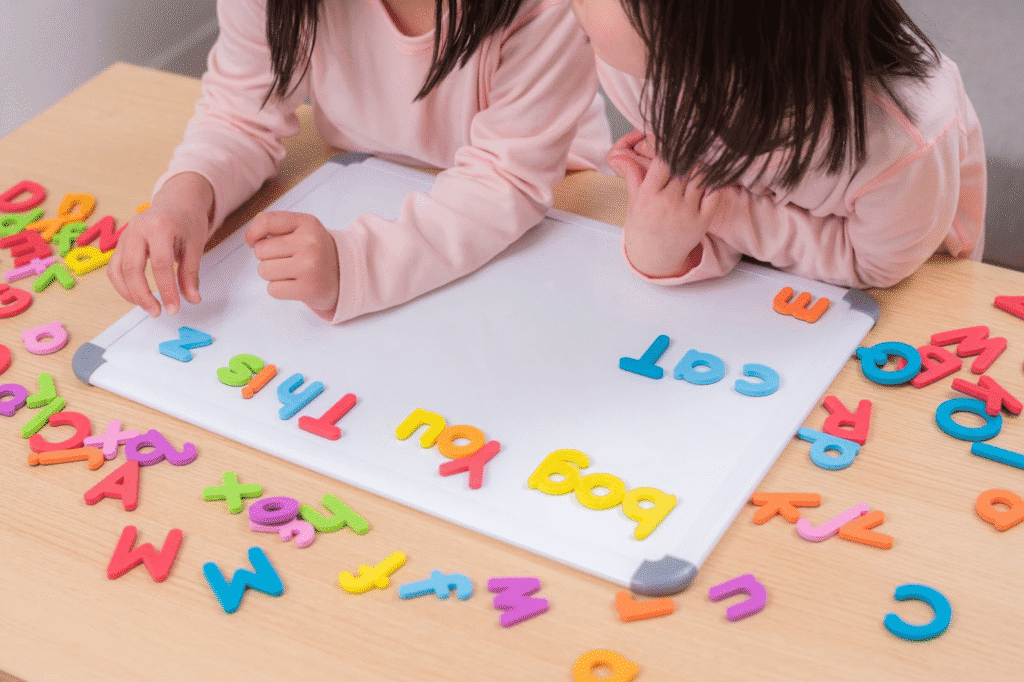 Crianças brincando com letras coloridas de alfabetização em sala de aula, aprendizado de letras e linguagem para crianças pequenas