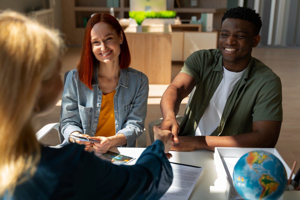 Homem e mulher apertando as mãos em uma mesa, simbolizando um acordo ou colaboração.